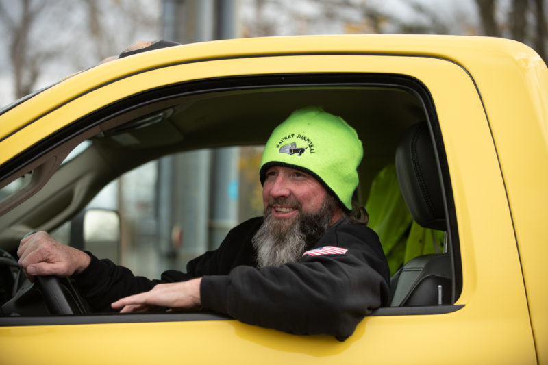 driver smiling and waving in a yellow truck