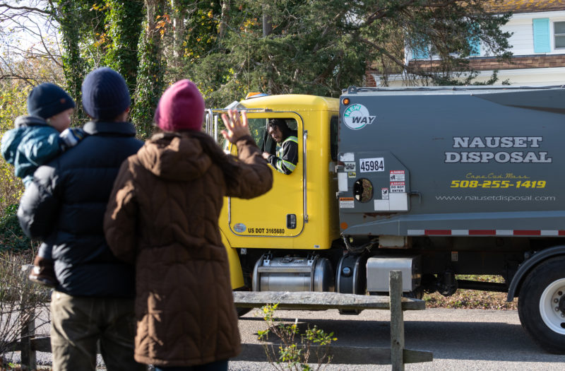 family waving to trash and recycling driver